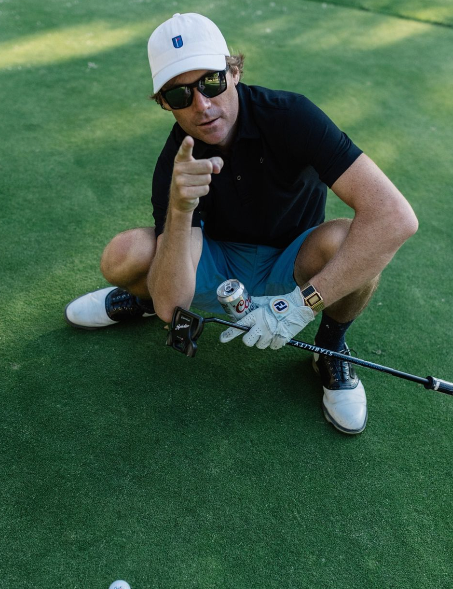 Golfer Squatting Down Next To His Cut Blue Ball Pointing At the Camera