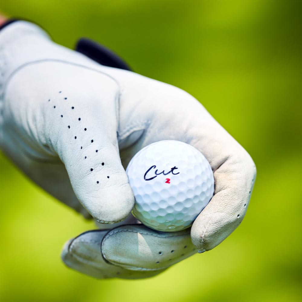 Golfer Holding a Cut Blue Golf Ball In a Gloved Hand