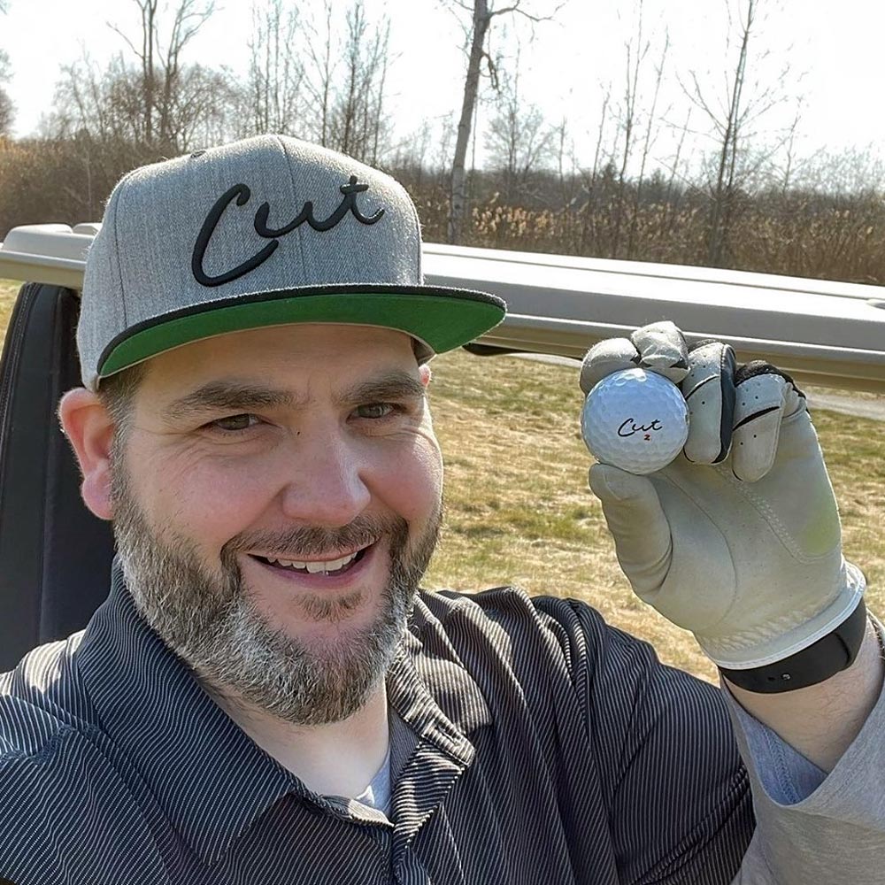 Golfer Smiling and Holding a Cut Red Golf Ball