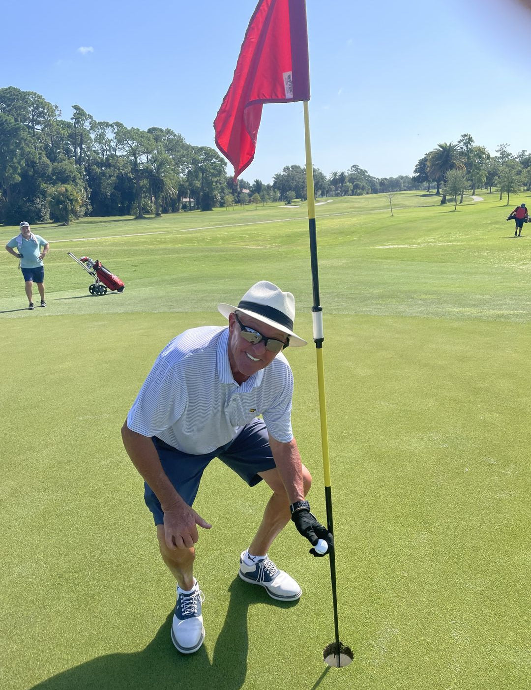 Golfer Grabbing His Cut Red Golf Ball Out of the Hole