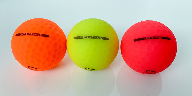 Three Matte Colored Golf Balls Lined Up