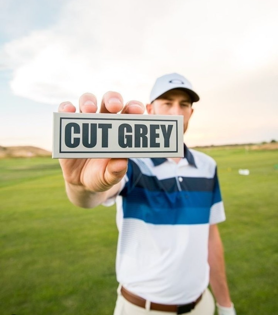 Golfer Holding a Cut Grey Sleeve of Golf Balls Out In Front
