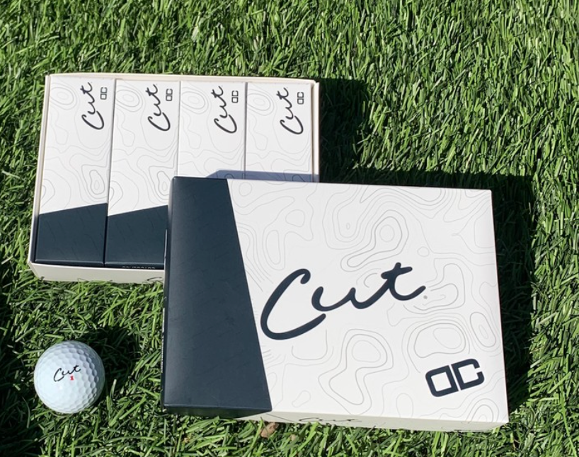 A Box of Cut DC Golf Balls With a Sleeve Next to It and One Cut DC Ball