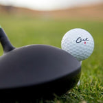 Cut DC Dual Core 4 Piece Golf Ball On Tee With Driver Next To It